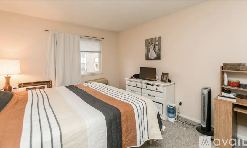 A bedroom with two beds, a desk, and a fan.