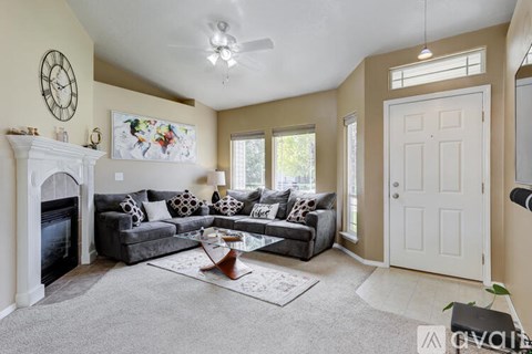 A living room with a grey couch and a fireplace.