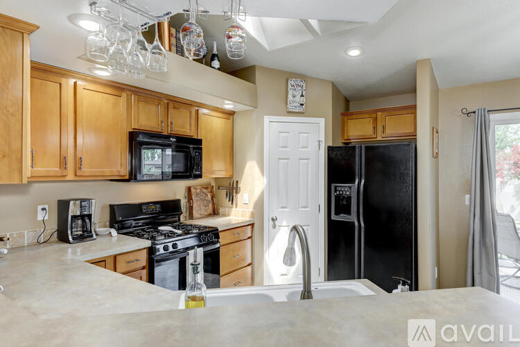 A kitchen with wooden cabinets and a black refrigerator.