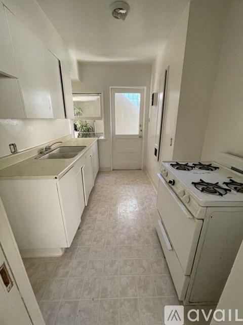 A kitchen with white cabinets and a white stove.
