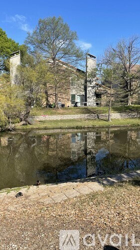 A building with a chimney is reflected in a body of water.