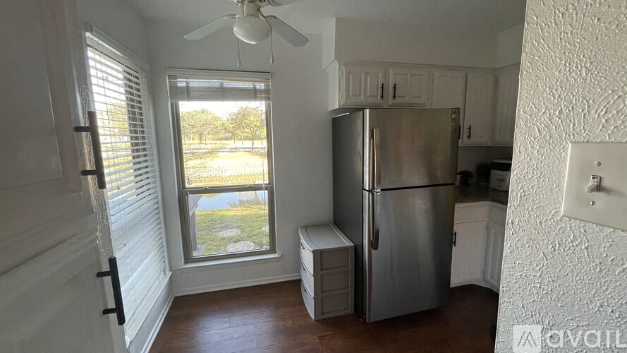 A kitchen with a refrigerator and a window with blinds.