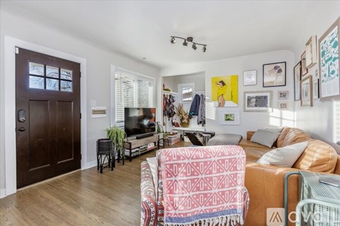 A living room with a brown door and a couch with a pink and white blanket on it.