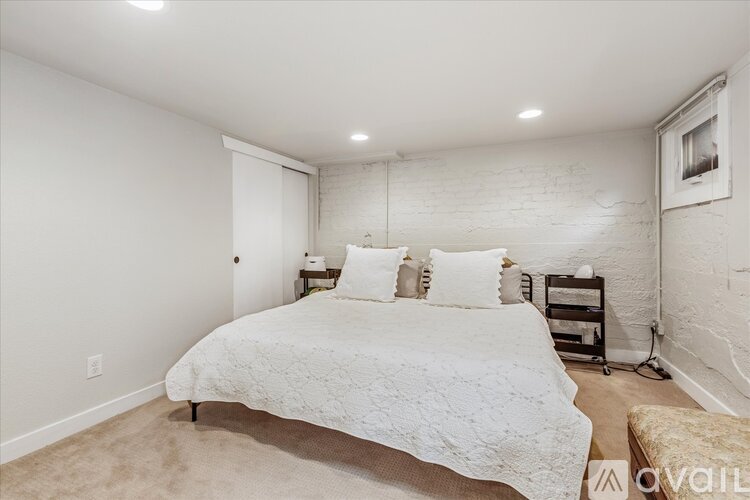 A bedroom with a white bed and a white brick wall.