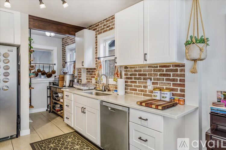 A kitchen with white cabinets and a brick wall.