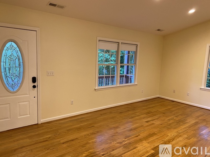 A room with a white door and a window with a view of trees.
