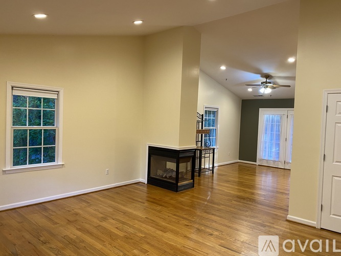 A spacious room with wood flooring and a fireplace.