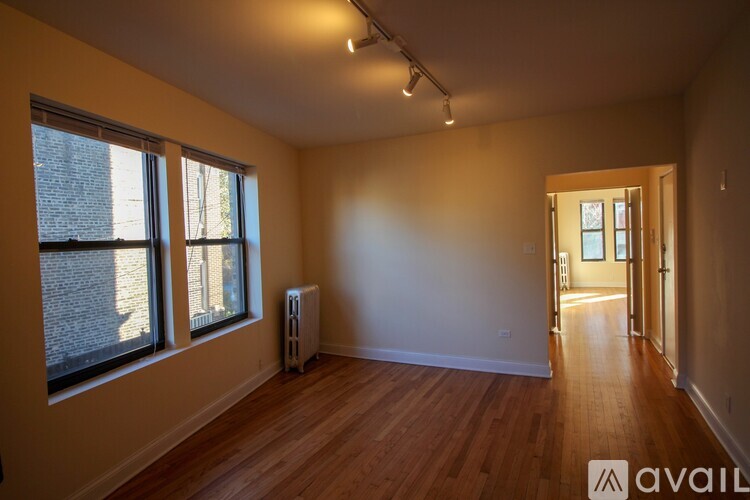 A room with wooden floors and a window with a view of a brick building outside.
