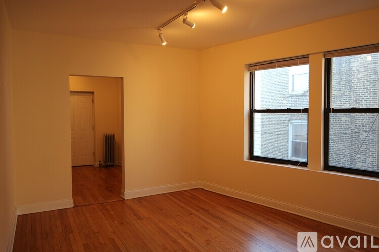 A room with wooden floors and a window showing a brick wall outside.