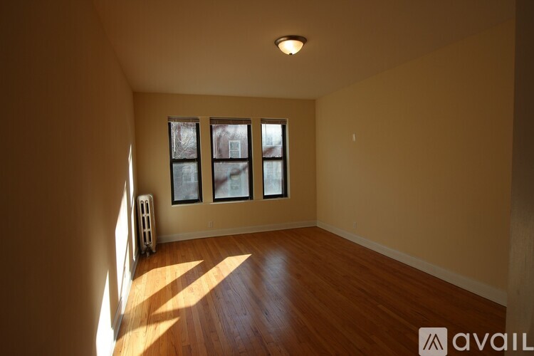 A room with wooden floors and a window with a view of a building outside.