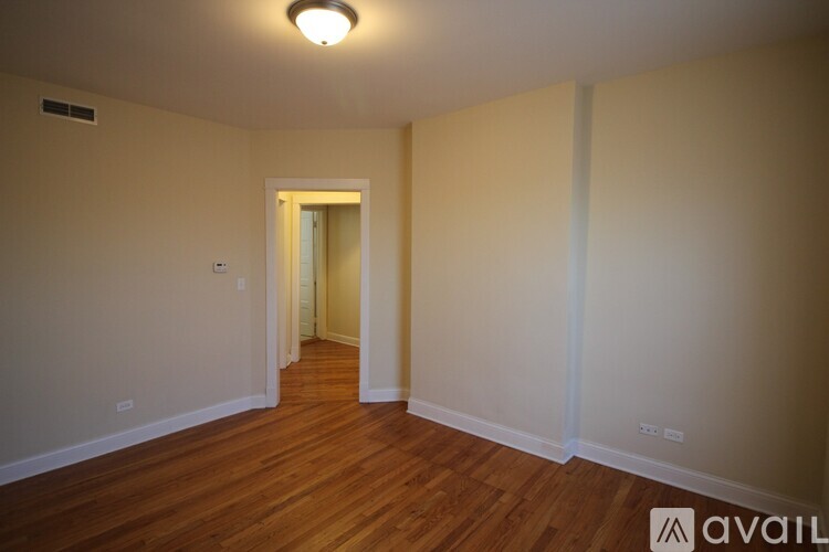A room with wooden floors and a doorway leading to another room.