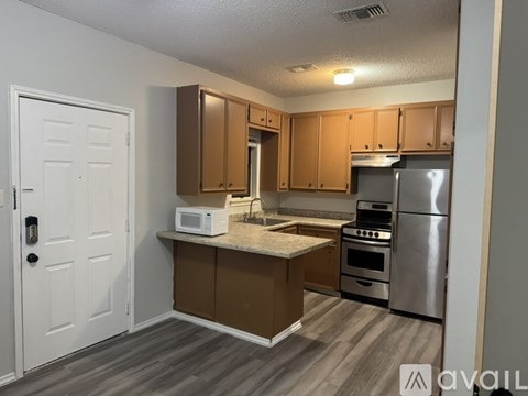 A kitchen with a white door, brown cabinets, and a stainless steel refrigerator.