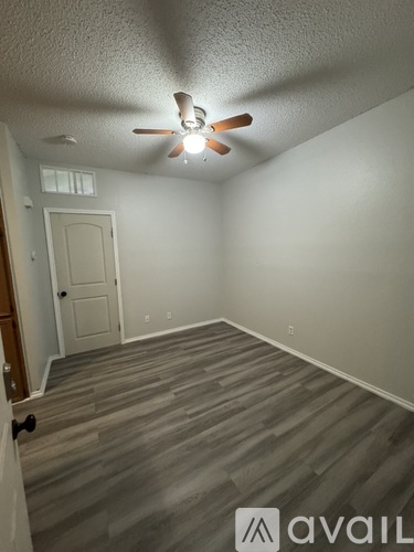A room with a ceiling fan and wooden flooring.
