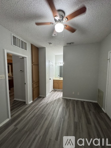 A room with a ceiling fan and wooden flooring.