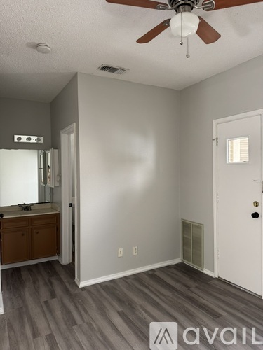 A room with a ceiling fan and a door leading to another room.