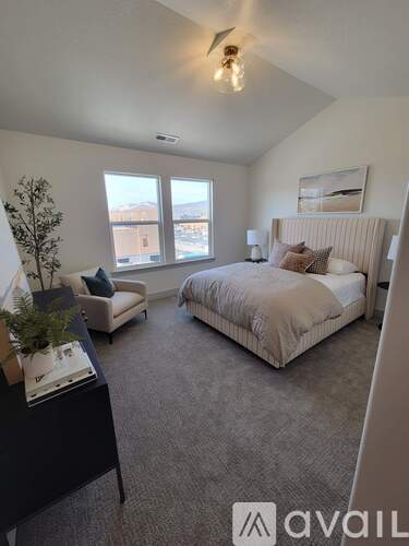 A bedroom with a large bed and a chair with a plant on a table.