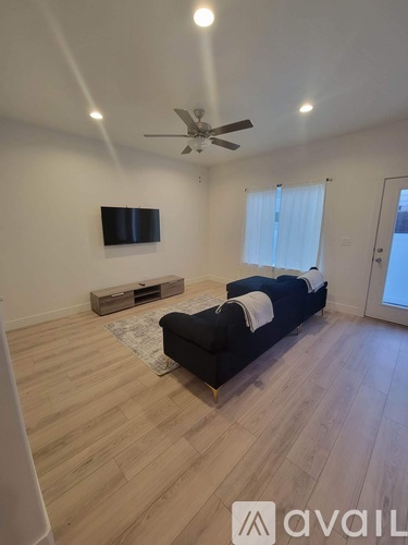 A living room with a black couch and a flat screen TV mounted on the wall.