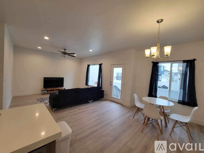A living room with a black couch, a television, and a dining table with chairs.