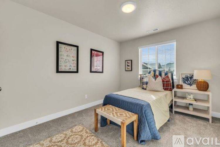 A bedroom with a bed, a bench, and two pictures on the wall.