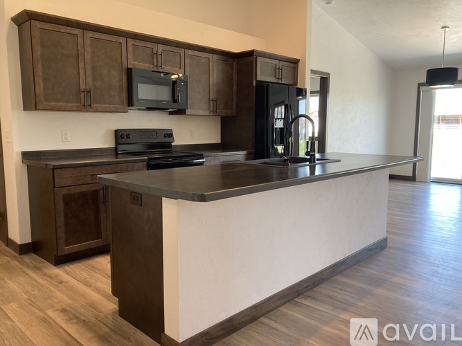 A kitchen with dark wood cabinets and a black countertop.