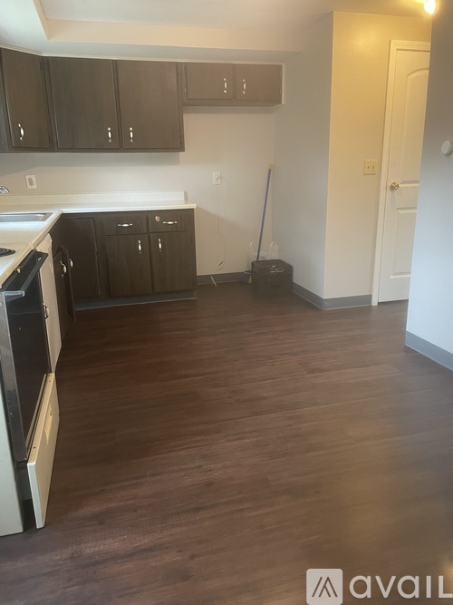 A kitchen with dark wood floors and white walls.