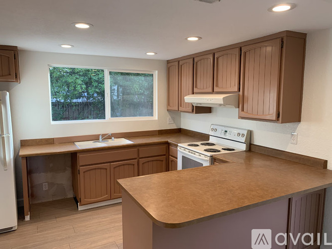 A kitchen with brown cabinets and a white stove top oven.