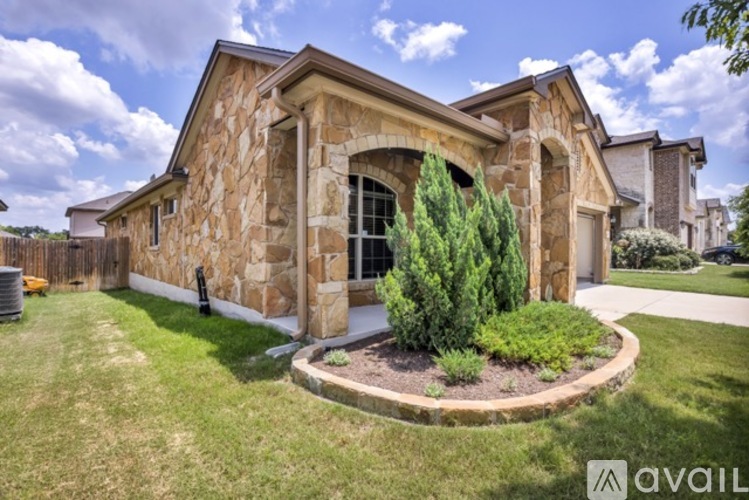 A house with a stone facade and a green lawn in front.