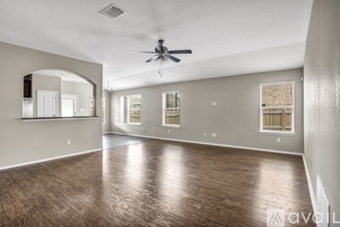 A spacious room with a ceiling fan and wooden flooring.