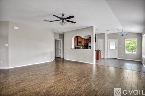 A spacious living room with a ceiling fan and hardwood floors.