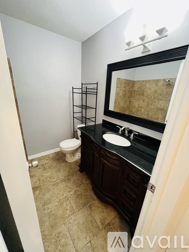 A bathroom with a toilet, sink, and mirror.