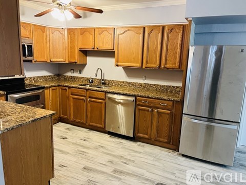 A kitchen with wooden cabinets and a stainless steel refrigerator.