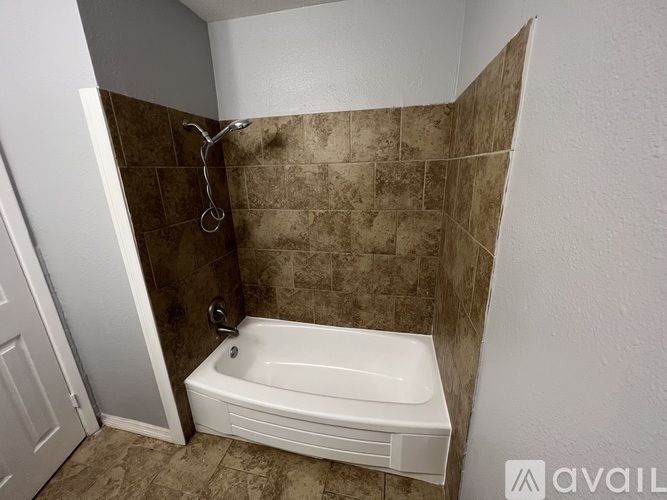 A bathroom with a tiled shower and a white bathtub.