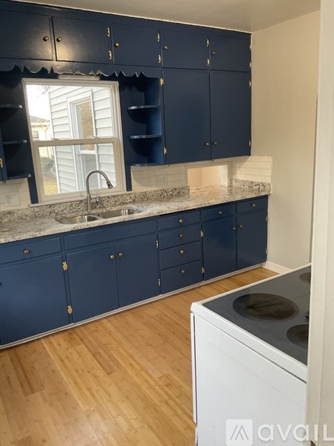 A kitchen with dark blue cabinets and a white dishwasher.