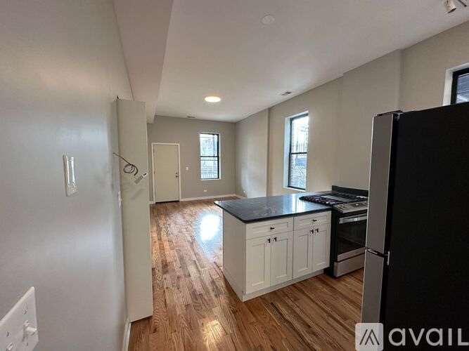 A kitchen with white cabinets and a black fridge.