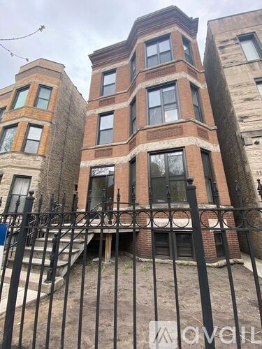A tall brick building with a black iron fence in front.