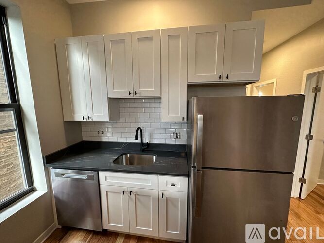 A kitchen with white cabinets and a stainless steel refrigerator.