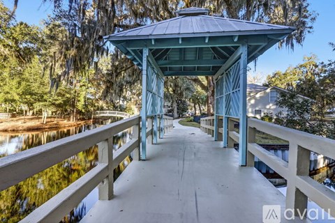 A gazebo-like structure with a roof and pillars is situated on a bridge over a body of water.