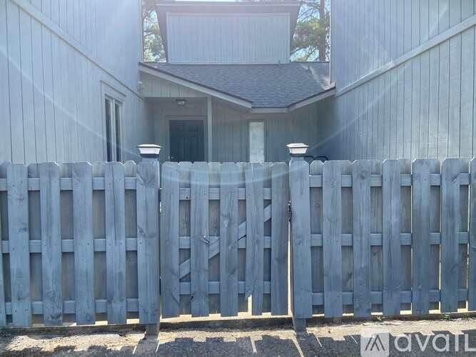 A wooden fence in front of a house with a sign that says "available".