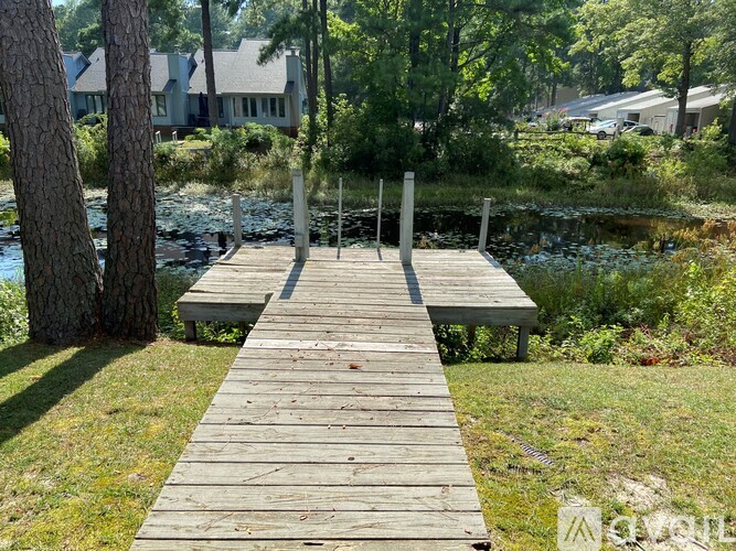 A wooden walkway leads to a body of water surrounded by greenery.
