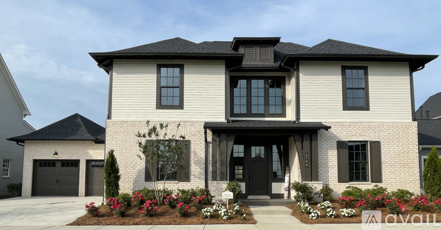 A two-story house with a black roof and a front porch.