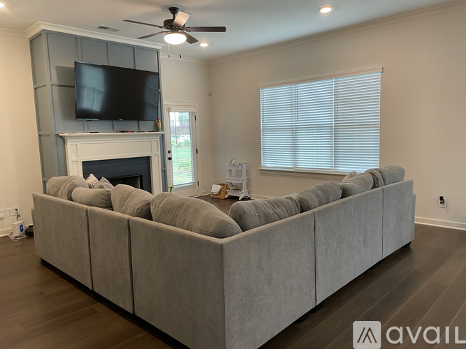 A living room with a grey couch and a television mounted above the fireplace.