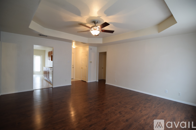 A spacious room with a ceiling fan and wooden flooring.