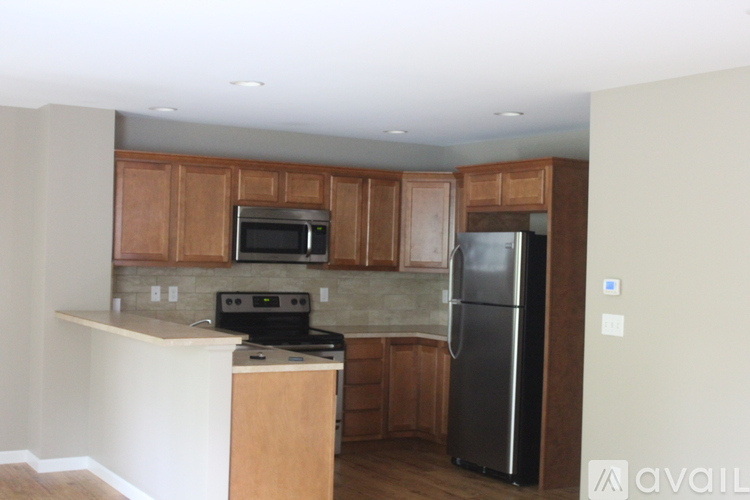 A kitchen with wooden cabinets and a black refrigerator.