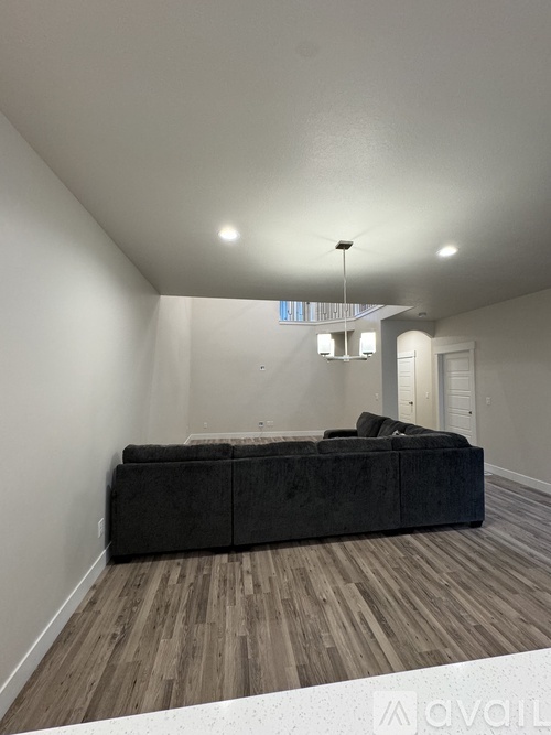 A living room with a grey couch and wooden flooring.