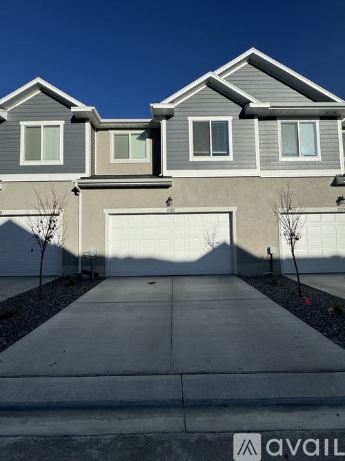A modern house with a grey and white exterior and a large driveway.
