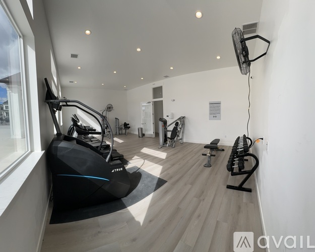 A modern gym with a row of treadmills and elliptical machines.