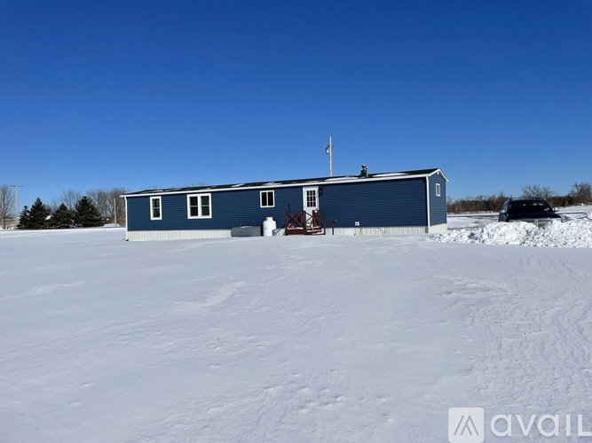 A blue building with a flag on top is surrounded by snow.