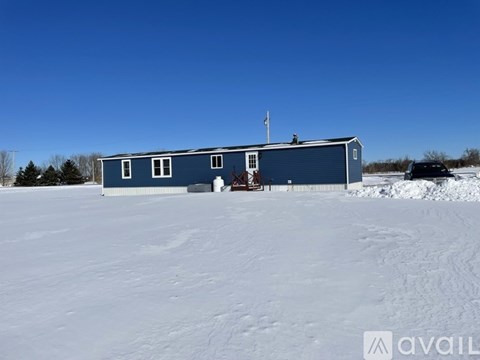 A blue building with a flag on top is surrounded by snow.