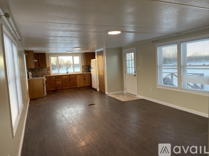 A spacious living room with wood flooring and a large window.