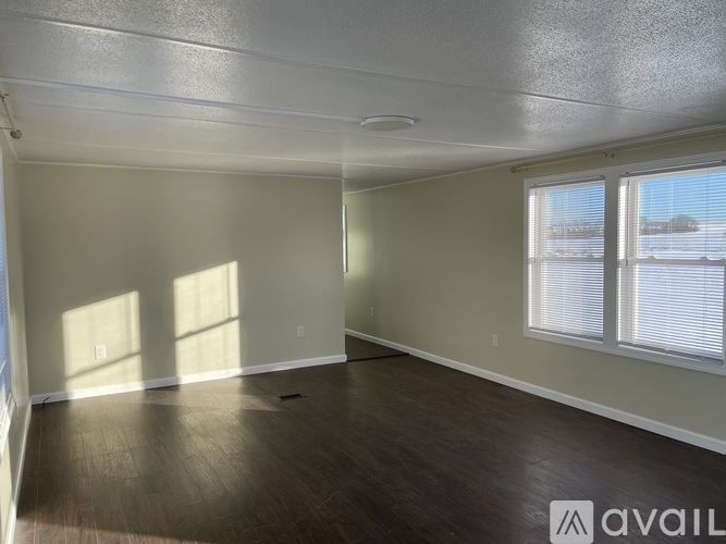 A spacious room with wooden flooring and a large window.